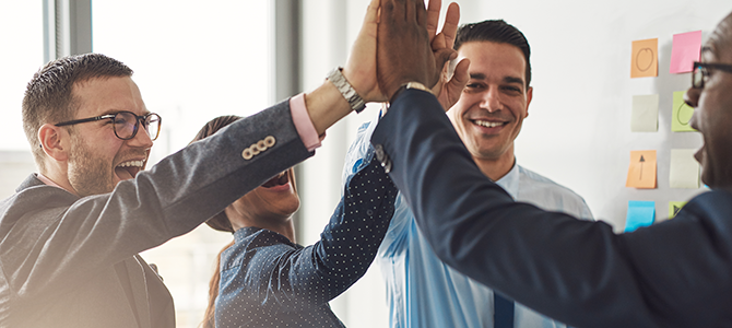 a group of people in business attire high-five each other.