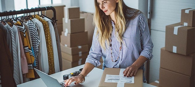 Gig Economy-02 woman standing over a laptop with shipping boxes around her